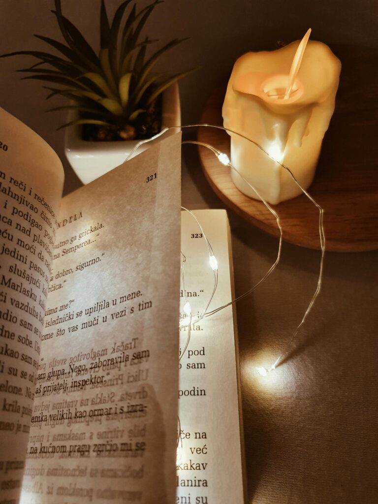 A book open with string lights and candle, creating a cozy reading atmosphere.